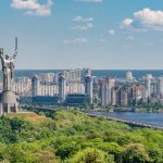 motherland monument among green trees on embankment in kiev