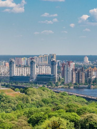 motherland monument among green trees on embankment in kiev